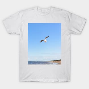 White seagull flying above the seacoast T-Shirt